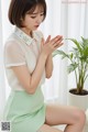 a woman sitting on top of a white table next to a plant