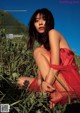 A woman in a red dress sitting in a field.