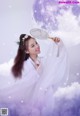 A woman in a white dress holding a fan in the clouds.