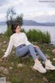 A woman sitting on a rock by the water.