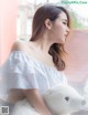 A woman sitting on a window sill holding a teddy bear.