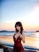 A woman in a red bathing suit standing on a beach.