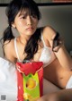 A woman sitting on a bed holding a bag of chips.