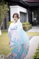 A woman in a blue kimono holding a blue umbrella.