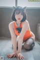 A woman in an orange bathing suit crouching on the floor.