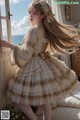 A girl in a white dress standing by a window.